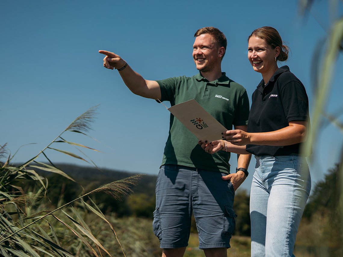 Zwei Mitarbeiter auf einer Klärschilfanlage, Mann zeigt auf etwas