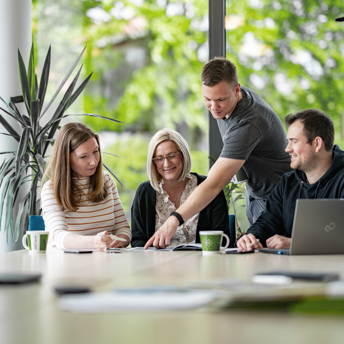 Klärschilf Mitarbeiter sitzen zusammen an einem Tisch, Mann zeigt auf Papier auf Tisch
